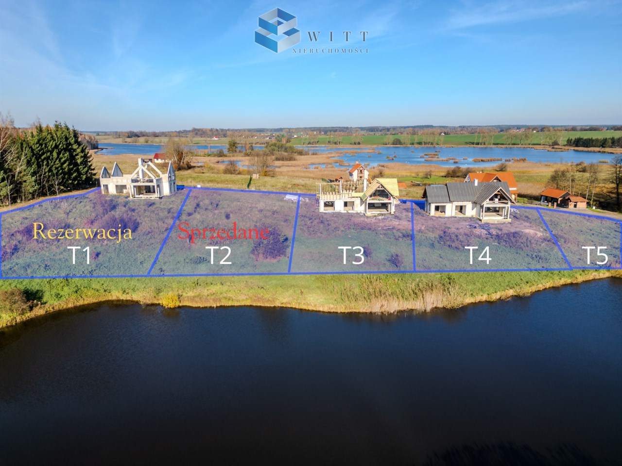 Widok na działki budowlane nad jeziorem, z oznaczeniami rezerwacji i sprzedaży: T1 (rezerwacja), T2 (sprzedane), T3, T4, T5. W tle malownicza panorama z zielonymi polami i wodami.