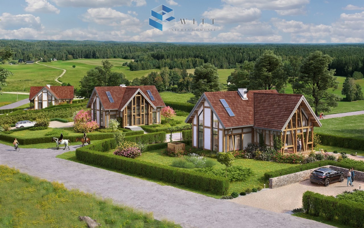 Widok na nowoczesne domy jednorodzinne w malowniczej okolicy, otoczone zielonymi działkami, drzewami i kwiatami. W tle rozciągają się tereny wiejskie, a na drodze widać rowerzystów i jeźdźców na koniach. W prawym dolnym rogu stoi samochód.