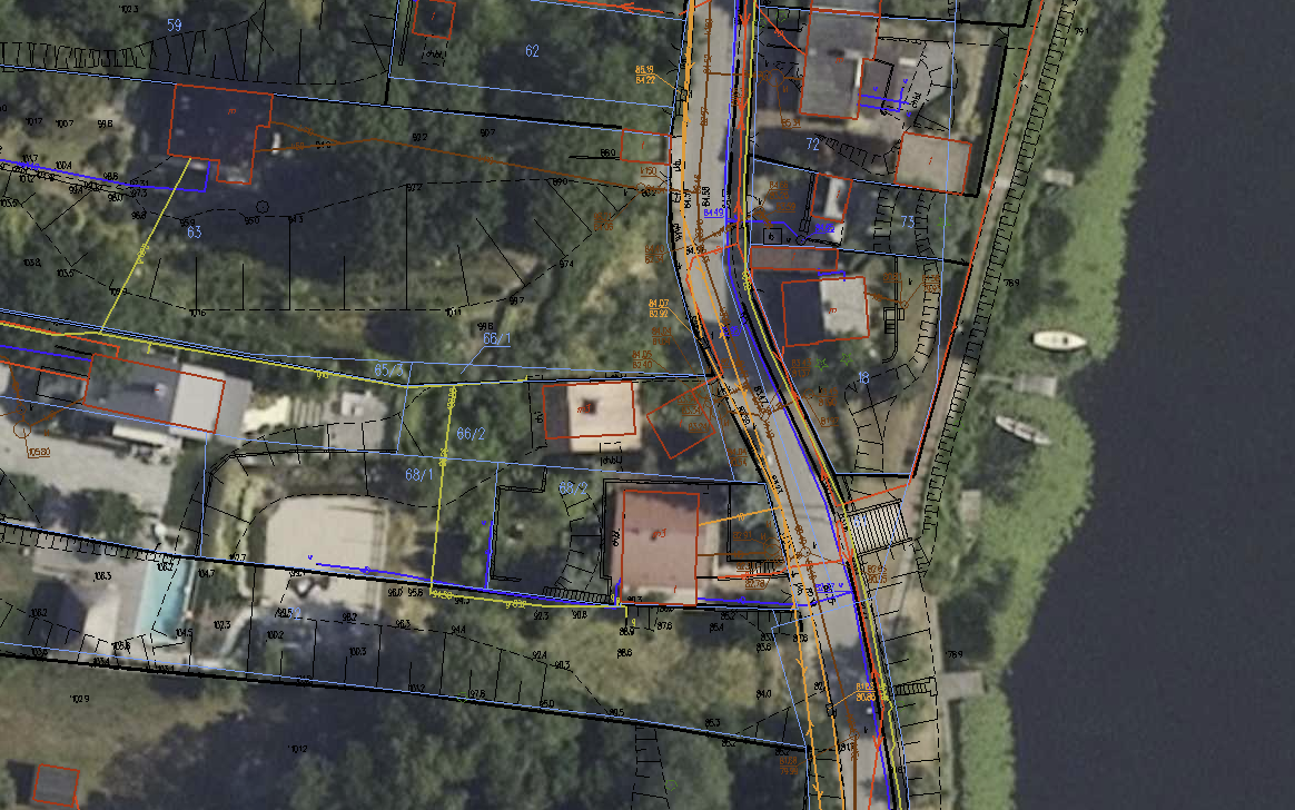 Mapa terenu z zaznaczonymi działkami, budynkami i infrastrukturą drogową w okolicy rzeki. Widoczne są granice działek, numery budynków oraz elementy otoczenia, takie jak droga i nabrzeże.